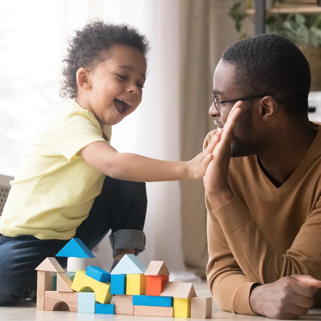 African American Father With Toddler Son Playing With Wooden Con
