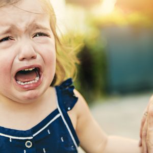 Close Up Portrait Of Crying Little Toddler Girl With Outdoors Ba