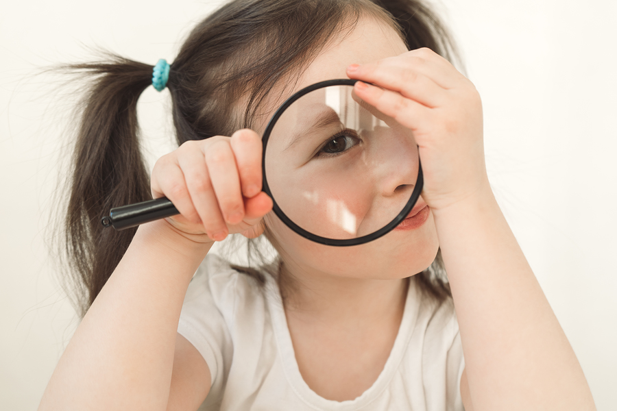 little girl plays a detective. a child examines something throug
