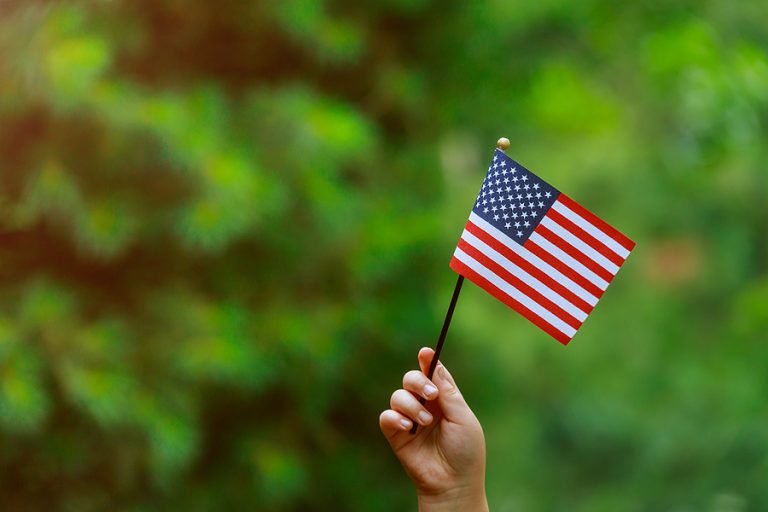 beautiful american flag in her hand laughing on sunny day indepe
