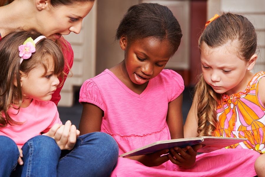 children learning to read with nursery teacher in preschool