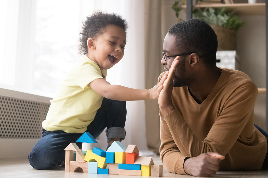 african american father with toddler son playing with wooden con