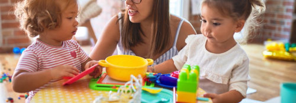 Young Beautiful Teacher And Toddlers Playing Meals Using Plastic